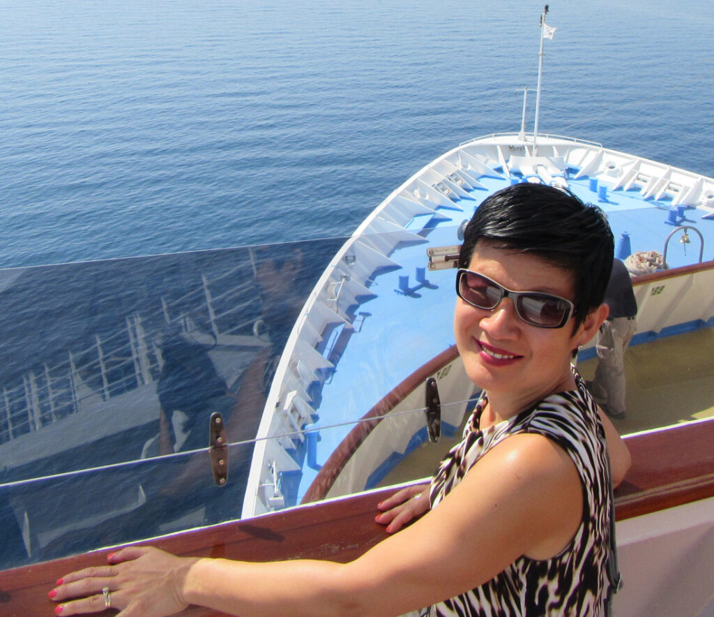 Travel Journalist Ming Tappin stands on the bow of a cruise ship.